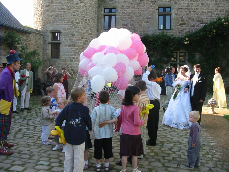 Wedding couple look at the clown and children preparing the release of balloons