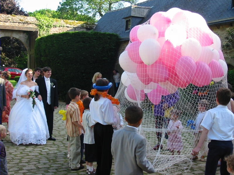 Wedding couple look at the clown and children preparing the release of balloons